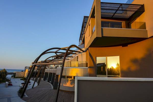 Außenansicht des Cretan Dream Resort & Spa mit Gebäuden und Meer im Hintergrund.