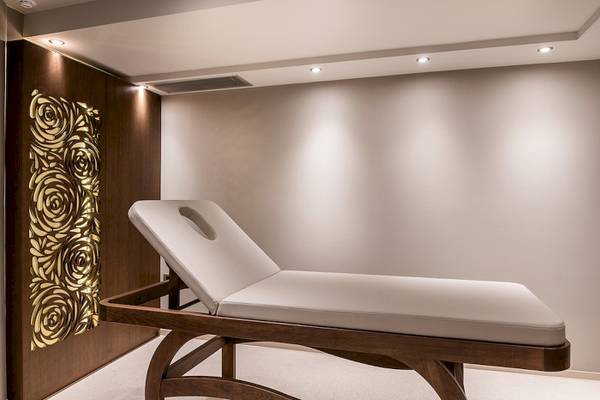 Behandlungsraum im Cretan Dream Resort & Spa mit weißer Liege und goldener Wandgestaltung
