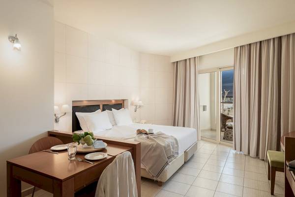 Innenansicht eines Zimmers im Cretan Dream Resort & Spa Hotel mit einem Bett, Tisch und Balkon