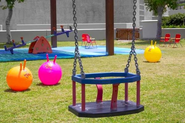 Kinderspielplatz im Sheraton Rhodes Resort mit Schaukel, bunten Bällen und Spielgeräten.