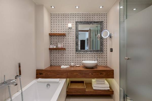 Ein Badezimmer im Cretan Dream Resort & Spa mit Badewanne, Waschbecken, Spiegel und gefliester Wand.