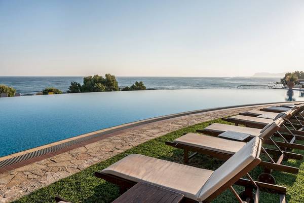 Außenpool mit Sonnenliegen am Cretan Dream Resort & Spa mit Blick auf das Meer.