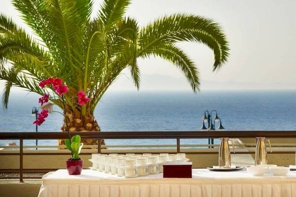 Szene auf dem Balkon des Sheraton Rhodes Resort mit Blick auf das Meer und Palmen.