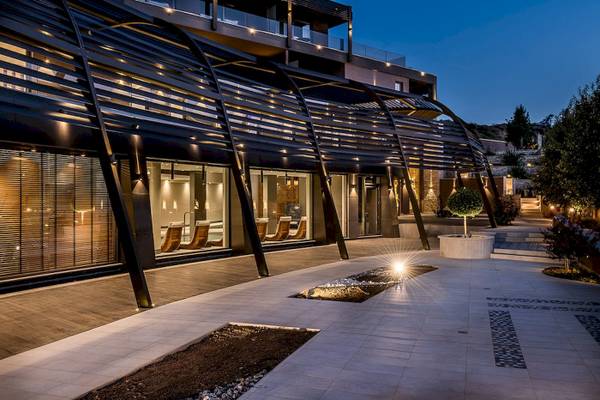 Die Außenansicht des Cretan Dream Resort & Spa bei Nacht mit einer gebogenen Pergola und beleuchteten Innenräumen.