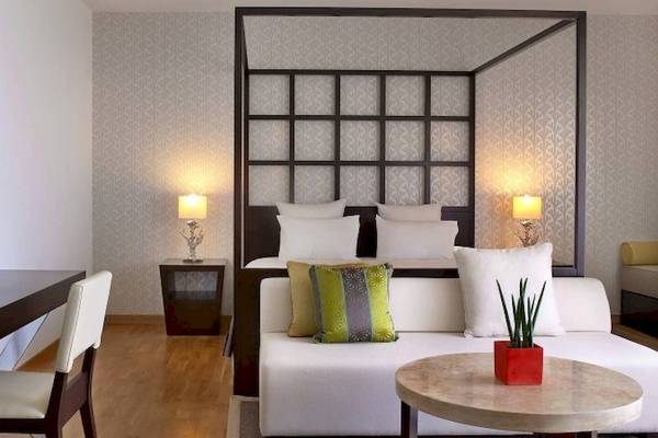 Interieur des Schlafzimmers im Sheraton Rhodes Resort mit Bett, Schreibtisch und Pflanzen.
