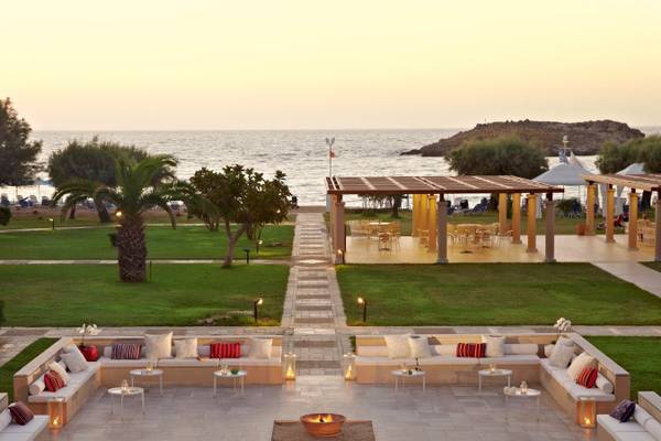 Außenbereich des Grecotel Meli Palace mit Blick auf das Meer bei Sonnenuntergang.