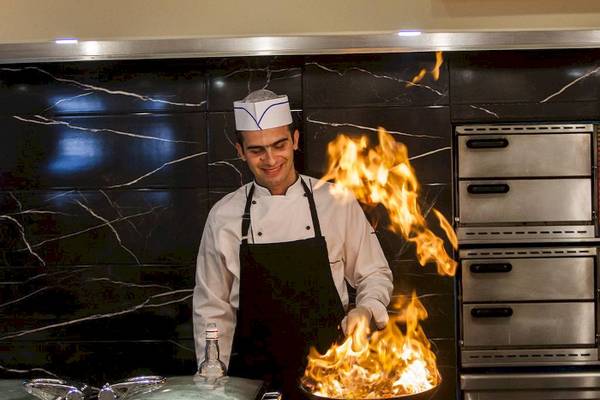 Koch im Chrissi Amoudia Hotel mit brennenden Flammen in der Küche