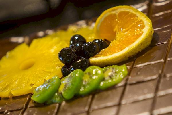 Nahaufnahme einer Schokoladenplatte mit Ananas, Kiwi, Blaubeeren und Orangenscheibe im Chrissi Amoudia Hotel.