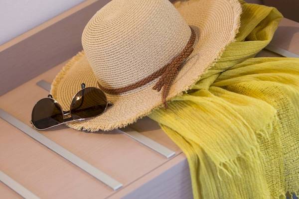 Sommer-Accessoire wie Hut und Sonnenbrille auf einem Tisch im Hotel Chrissi Amoudia