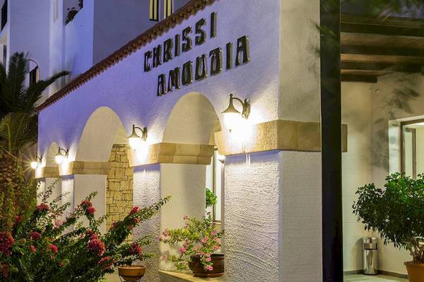 Das Chrissi Amoudia Hotel mit beleuchtetem Eingang und Pflanzen davor.