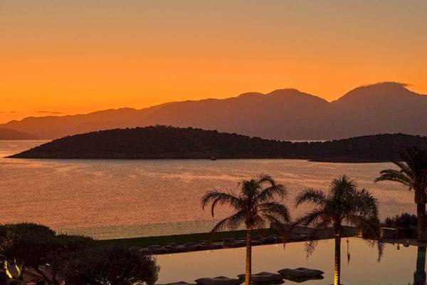 Abendlicher Sonnenuntergang im Hotel Minos Palace Hotel & Suites mit Blick auf das Meer und die Berge.