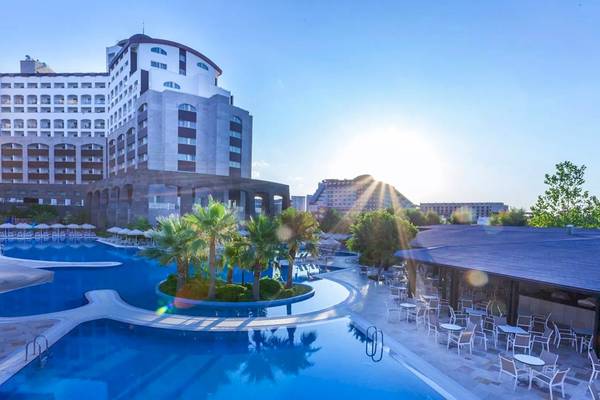 Das Melas Lara Hotel zeigt seinen Swimmingpool und eine Terrasse mit Tischen und Stühlen im Freien.