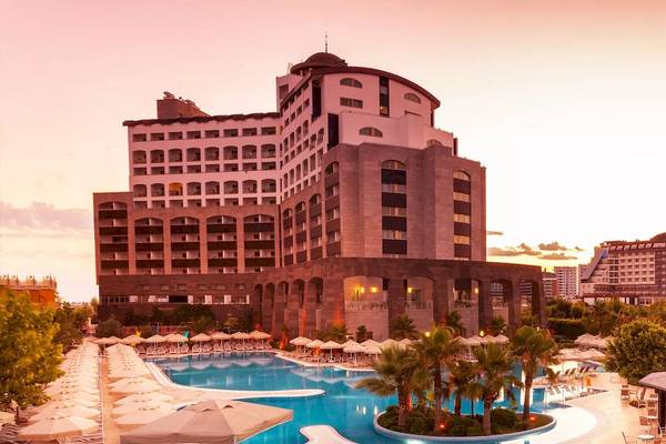 Melas Lara Hotel mit Swimmingpool und Palmen bei Sonnenuntergang