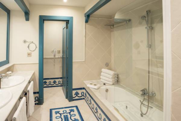 Badezimmer im LIVVO Volcan Lanzarote Hotel mit Badewanne und blauen Fliesen.