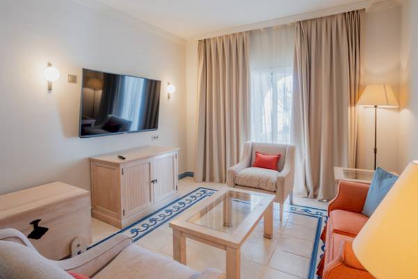 Wohnzimmer im LIVVO Volcan Lanzarote Hotel mit Fernseher, Couch und Tisch.