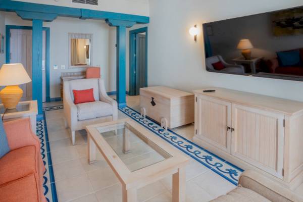 Wohnzimmer-Innenansicht im LIVVO Volcan Lanzarote Hotel mit Sofa, Couchtisch, Fernseher und Lampe.