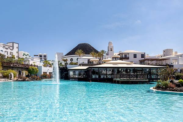 Außenpool des LIVVO Volcan Lanzarote Hotels mit weißen Gebäuden im Hintergrund.