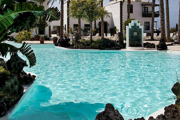 Außenpoolbereich des LIVVO Volcan Lanzarote Hotels mit Palmen und weißen Gebäuden