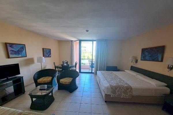 Zimmer im Muthu Playa Varadero Hotel mit Bett, Tisch, Stühlen und Fernseher.