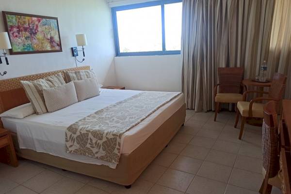 Hotelzimmer im Muthu Playa Varadero mit Bett, Fenster, Gemälde und Möbeln.