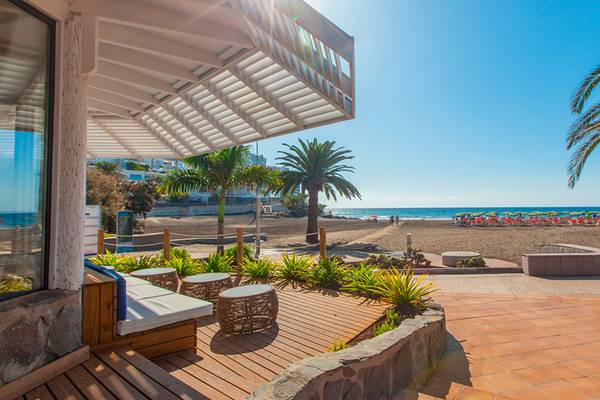 Aussicht auf den Corallium Beach von Lopesan Hotels mit Strand, Palmen und Sonnenschirmen.