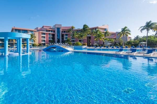 Der Außenpool des Muthu Playa Varadero Hotels mit vielen Liegestühlen und Palmen.