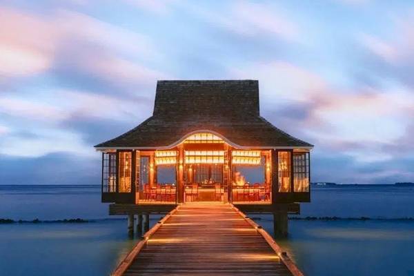 Nova Maldives Resort bei Nacht mit beleuchtetem Steg und illuminiertem Eingang