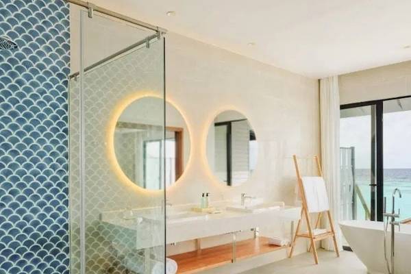 Badezimmer im Nova Maldives Hotel mit doppeltem Waschbecken und Badewanne mit Meerblick.