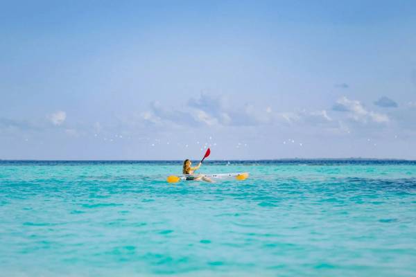Eine Frau paddelt auf dem Ozean vor dem Nova Maldives.