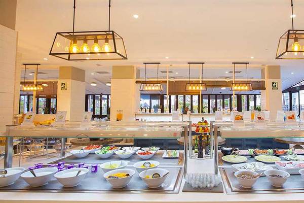 Buffetbereich im Corallium Beach Hotel mit vielen Speisen in weißen Schüsseln.
