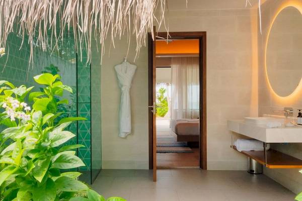 Außenbereich des Badezimmers im Nova Maldives mit grüner Wand und Dusche