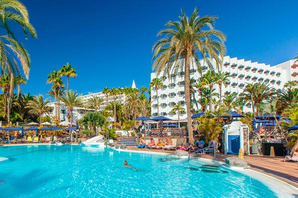 Außenpool des Corallium Beach by Lopesan Hotels mit Palmen und Sonnenschirmen.