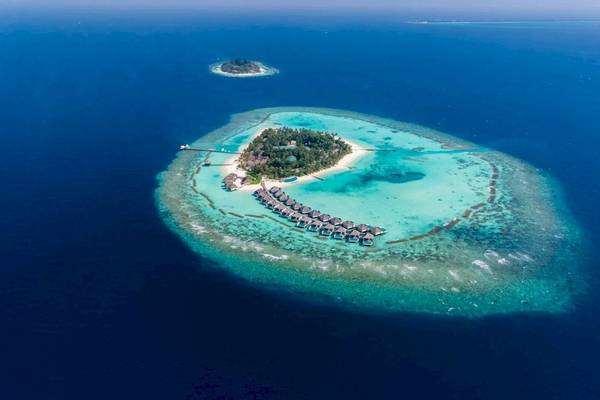 Luftaufnahme der Nova Maldives Insel mit Wasserbungalows und blauem Wasser