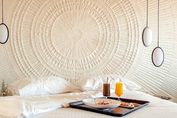 Bett im Mitsis Selection Rinela Hotel mit Frühstückstablett und Getränken