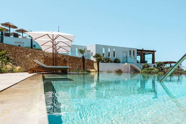 Außenpool des Mitsis Selection Rinela Hotels mit Liegestühlen und Sonnenschirmen.