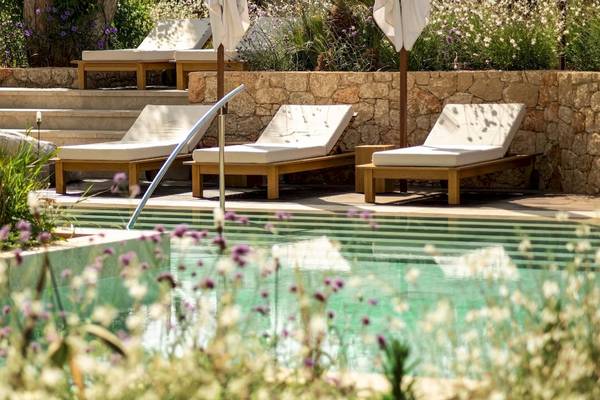 Pool-Lounge mit Sonnenliegen und Blumen am Mitsis Selection Rinela Hotel