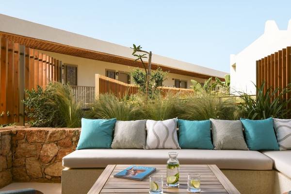 Außenbereich des Mitsis Selection Rinela Hotels mit einer Terrasse und einem Tisch.