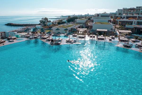 Luftaufnahme des Mitsis Selection Rinela Hotels mit mehreren Pools und Liegebereichen.