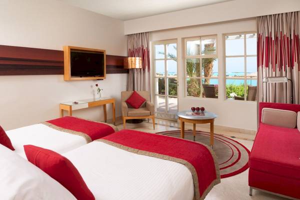 Zimmer im Mövenpick Resort & Spa El Gouna mit zwei Betten, rotem Dekor und Meerblick