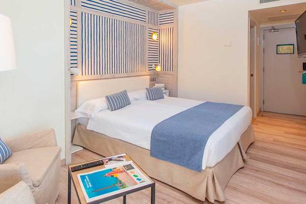 Bett im Hotelzimmer von Corallium Beach by Lopesan Hotels mit zwei Kissen, Decken und einem Nachttisch.