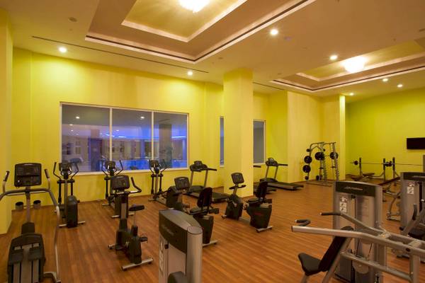 Fitness-Center im Defne Defnem Hotel mit verschiedenen Trainingsgeräten und einem Swimmingpool im Hintergrund.