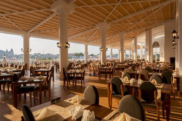 Innenansicht des Restaurants im Defne Defnem Hotel mit vielen gedeckten Tischen und Blick auf die Stadt.