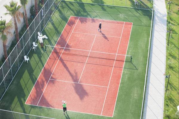 Zwei Personen spielen Tennis auf dem Tennisplatz im Freien im Defne Defnem Hotel.