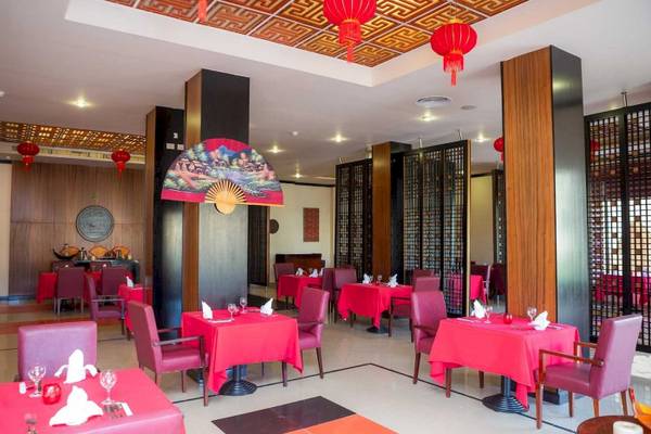 Restaurant im Stella Gardens Resort & Spa Makadi Bay mit roten Tischen und Stühlen.