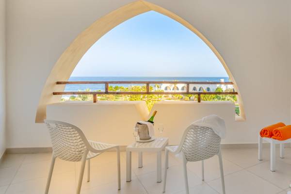 Balkon des Three Corners Equinox Beach Resort mit Blick auf das Meer und weiße Möbel.