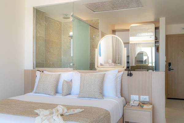 Schlafzimmer im Three Corners Equinox Beach Resort mit Bett und Badezimmerspiegel