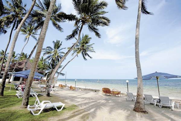 Strand des Kenya Bay Beach Hotel mit Liegen und Palmen im Schatten