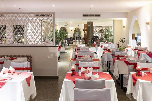 Restaurant-Innenbereich des Three Corners Equinox Beach Resorts mit gedeckten Tischen und roten Tischdecken.