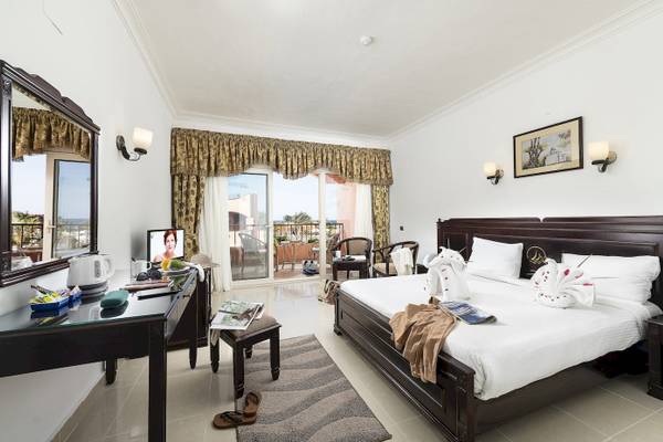 Hotelzimmer des Three Corners Happy Life Beach Resort mit Bett, Fernseher und Balkon.