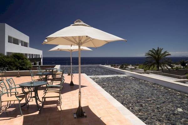 Terrasse des Costa Calero Thalasso & Spa mit Tischen, Stühlen und Sonnenschirmen